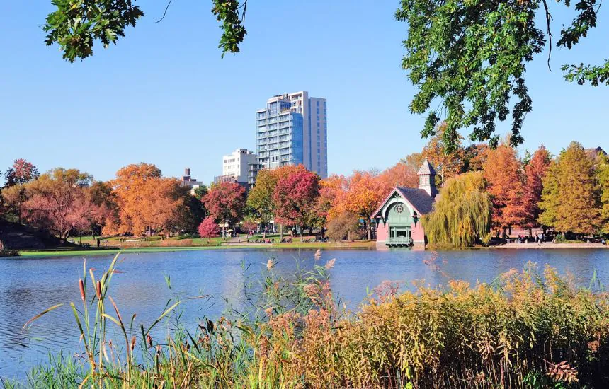 Autumn in Central Park north end in New York City Manhattan with buildings, lake and colorful foliage with clear blue sky.