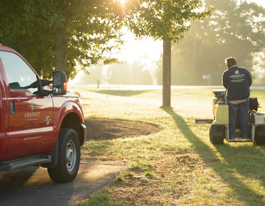 An arborist enterprises truck and their crew member doing some tree services and lawn care.